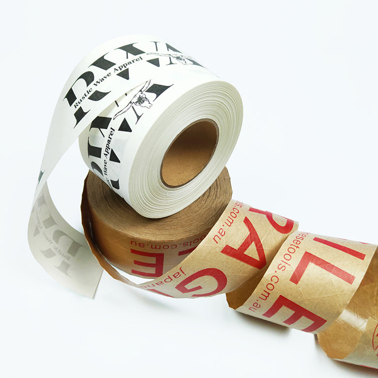 Rolls of custom eco-friendly water activated tape with visible text and patterns on the tape, placed against a neutral background.